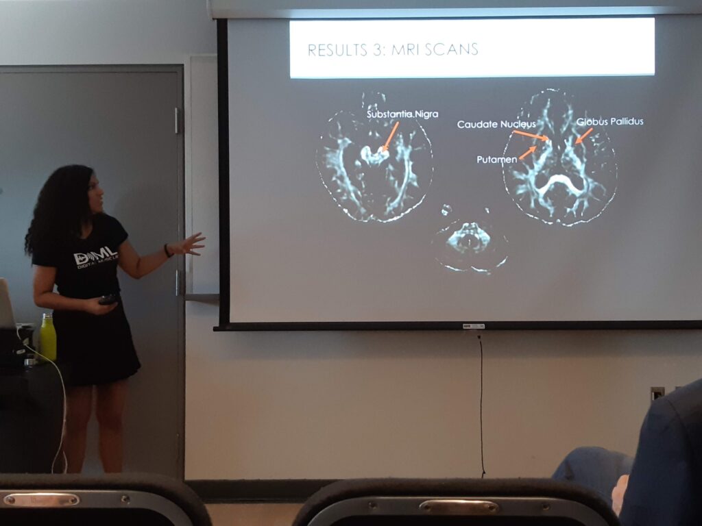 A student from DML presenting a slide of their research in front of a projector at ICMPC 2018.