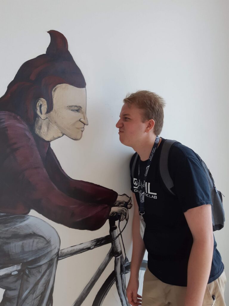 One of the McMaster Students at ICMPC 2018 posing next to a painting.