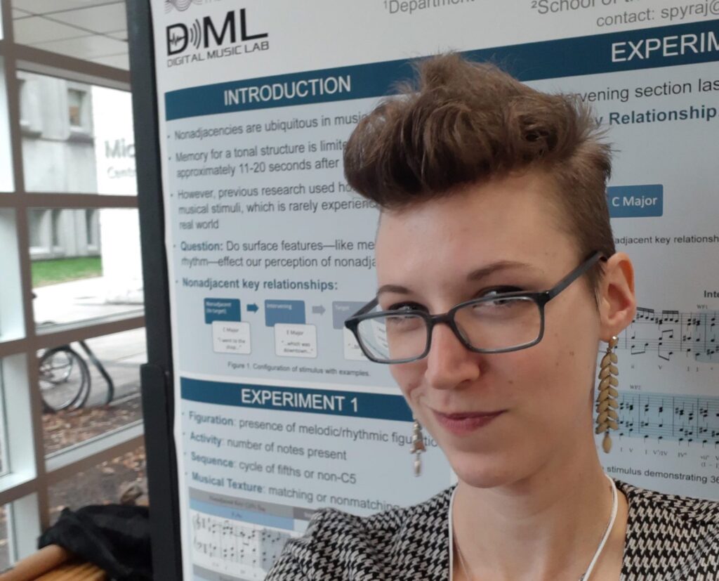 Jo Spyra taking a selfie in front of the poster they presented at MIMM 2019.